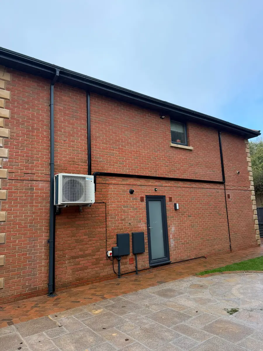 The outside of John’s home in Newport, showing the outdoor unit and neat black trunking